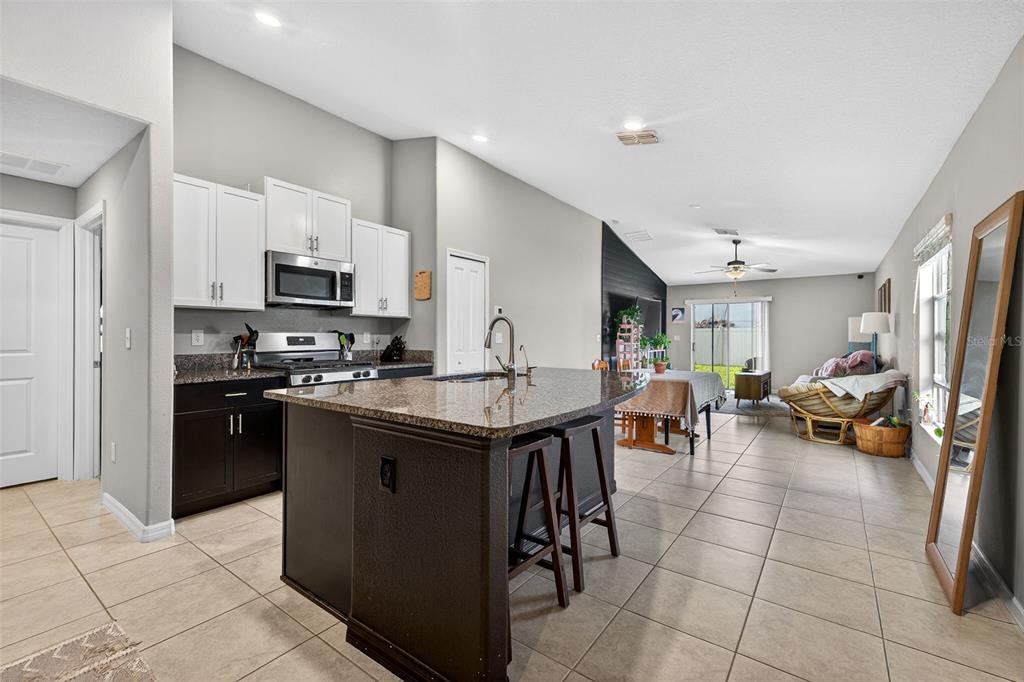 A kitchen with dark lower cabinets, white upper cabinets, and a granite-topped island with stools — 9324 LEMON DROP LOOP, SUN CITY CENTER, FL