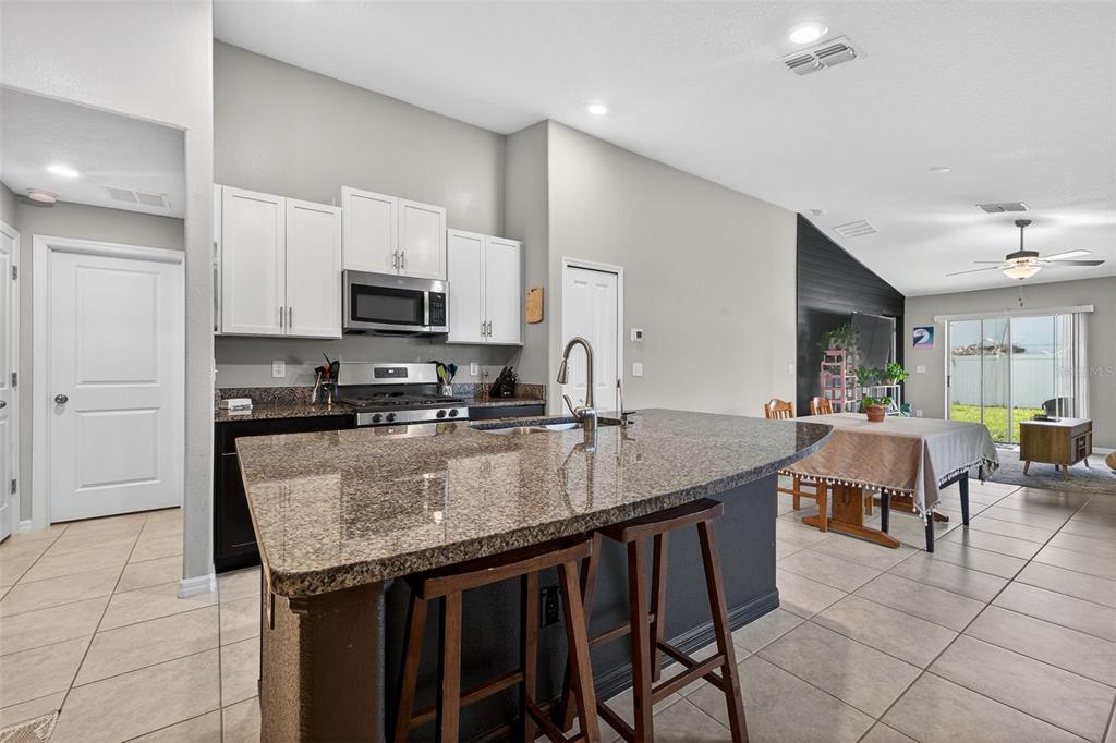 A kitchen with a granite-topped island, white upper cabinets, and tile flooring — 9324 LEMON DROP LOOP, SUN CITY CENTER, FL