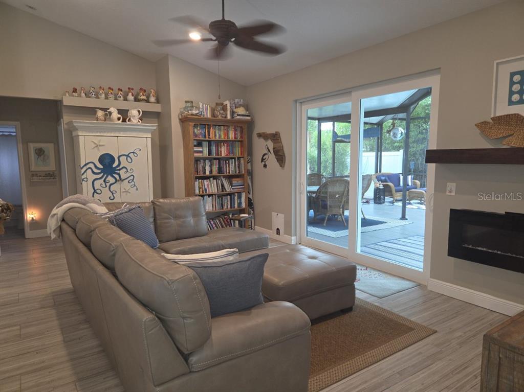 A living room features a gray sectional sofa, a bookshelf, a fireplace, and sliding glass doors — 1604 21ST AVENUE W, PALMETTO, FL