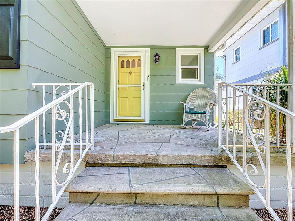 A green house with white-trimmed windows is surrounded by lush tropical trees and landscaping — 182 29TH AVENUE N, ST PETERSBURG, FL