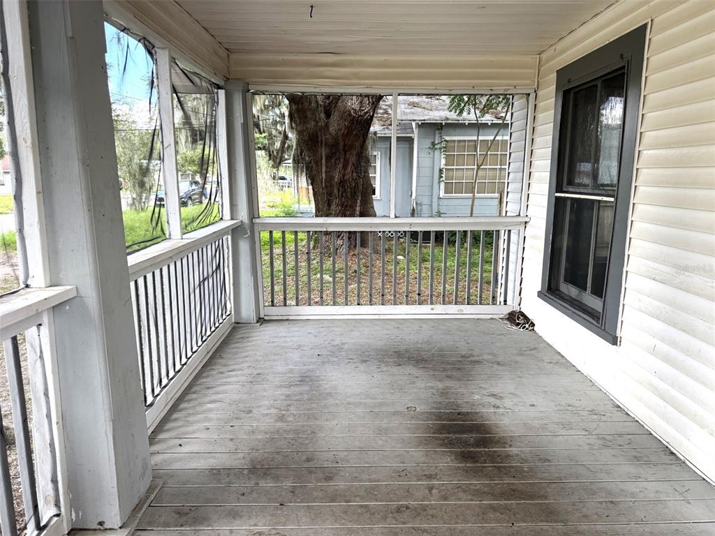 A covered wooden porch features a screened enclosure, white siding, and a view of trees — 1010 S DUDLEY AVENUE, BARTOW, FL