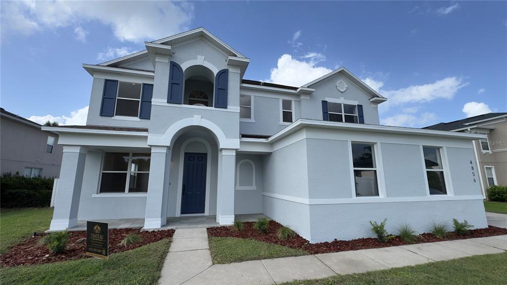 A two-story suburban house with light gray stucco siding and blue shutters — 4856 STONE ACRES CIRCLE, ST CLOUD, FL