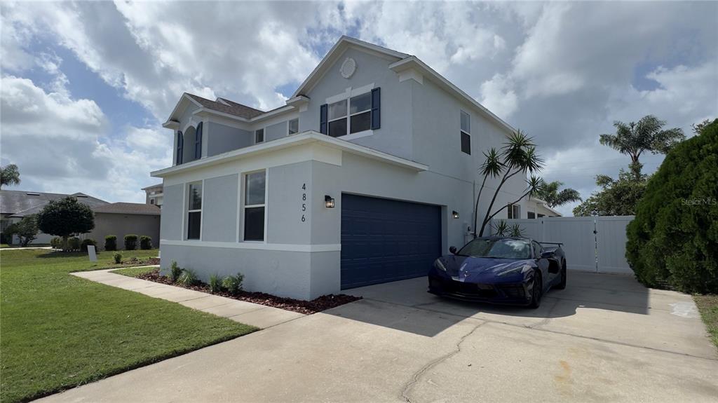 A two-story light gray house with blue shutters and a white fence under a sky — 4856 STONE ACRES CIRCLE, ST CLOUD, FL