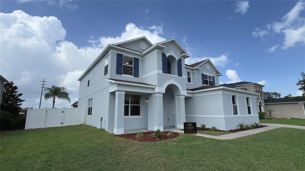 A two-story house with light gray stucco siding, blue shutters, and a white vinyl fence — 4856 STONE ACRES CIRCLE, ST CLOUD, FL