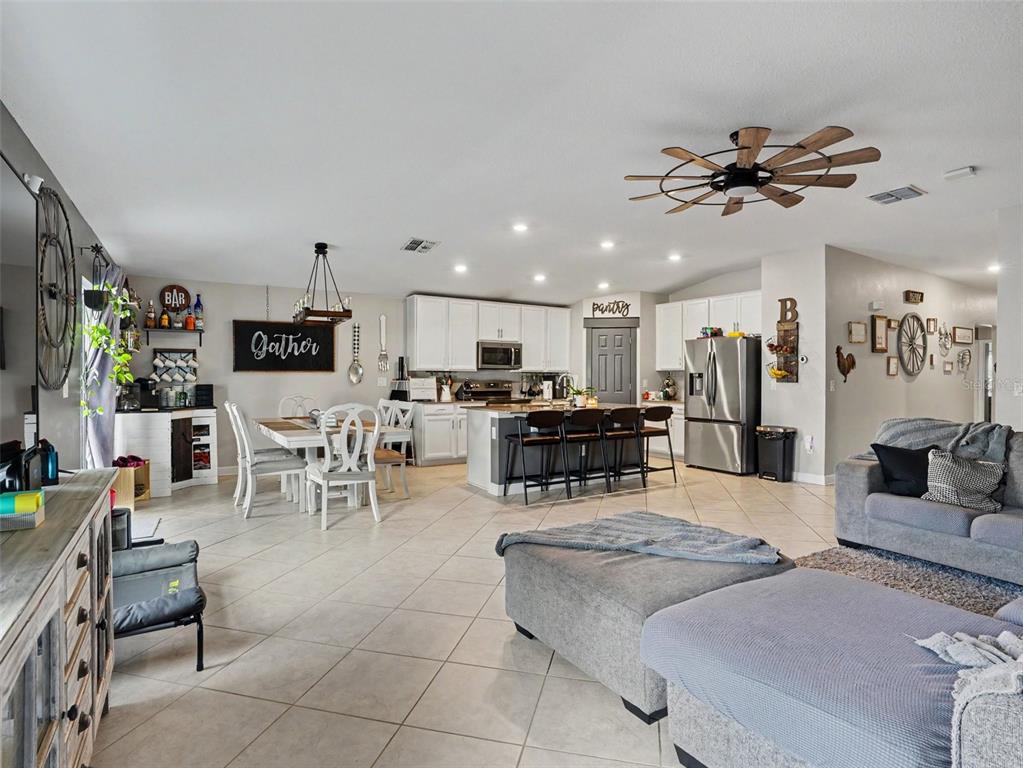 An open-concept kitchen and living area features white cabinetry, a central island, and tile flooring — 149 TAFT DRIVE, DAVENPORT, FL