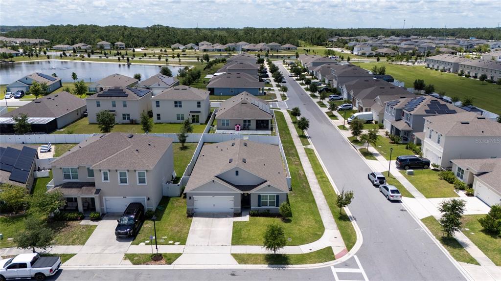 An aerial view shows a suburban neighborhood with single-family homes, paved streets, and a pond — 2845 ETHAN HAMMOCK ROAD, HARMONY, FL