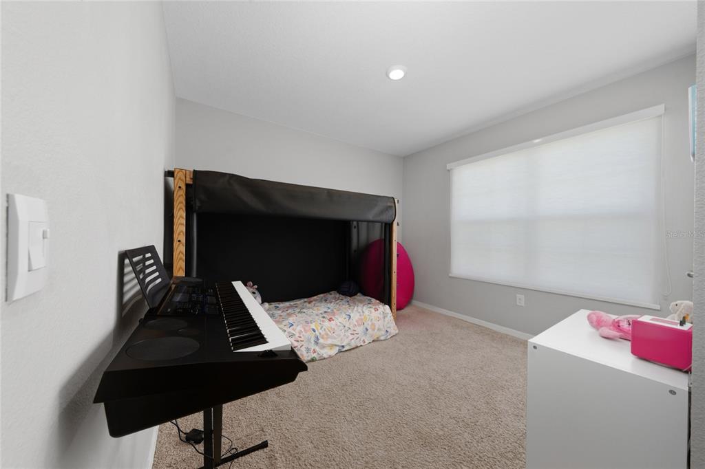 A bedroom features a keyboard on a stand, a bunk bed, and a white desk — 2845 ETHAN HAMMOCK ROAD, HARMONY, FL