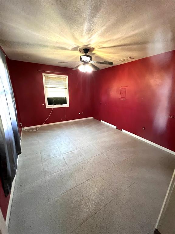 A bedroom with red walls, gray tile flooring, and a ceiling fan — 6586 NE MOORE AVENUE, ARCADIA, FL