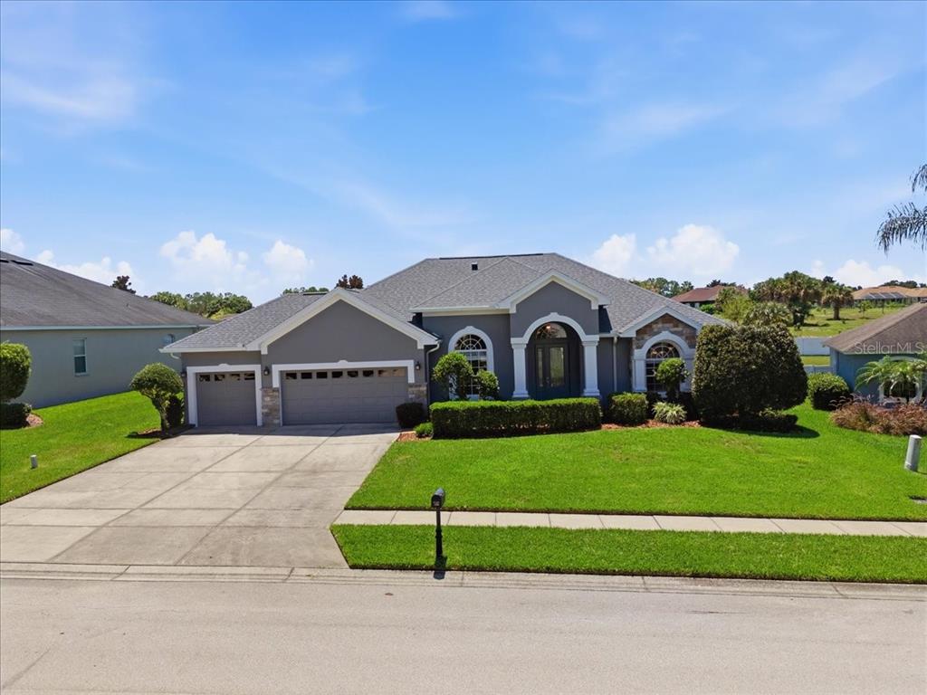 A single-story gray house with a three-car garage and a manicured lawn — 230 LAKE ARIETTA COURT, AUBURNDALE, FL