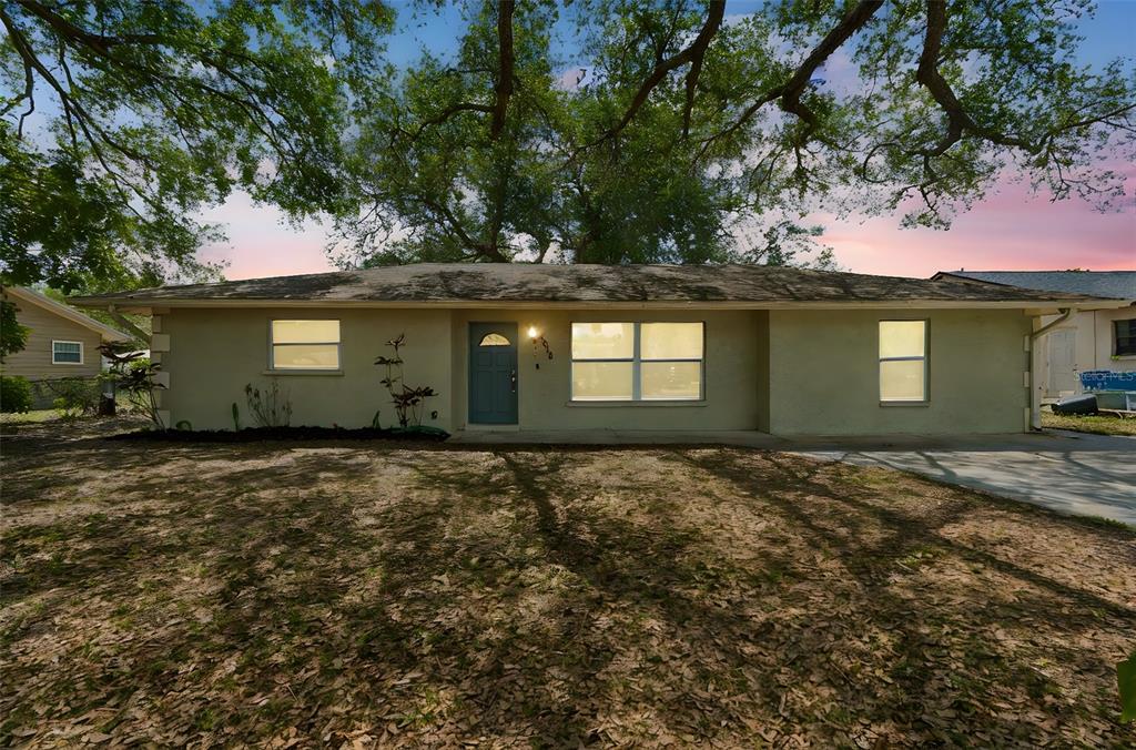 A single-story house with a light-colored stucco exterior sits under a large oak tree — 4018 PRADO DRIVE, SARASOTA, FL