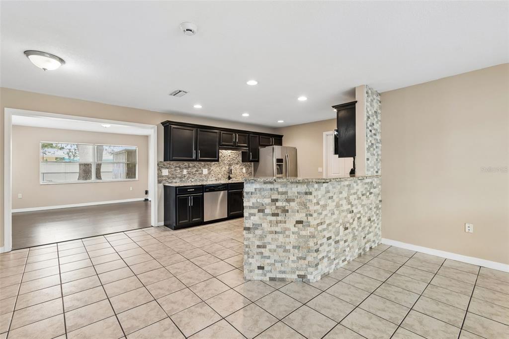 A kitchen features dark cabinets, a stone-tiled breakfast bar, and light-colored floor tiles — 4018 PRADO DRIVE, SARASOTA, FL