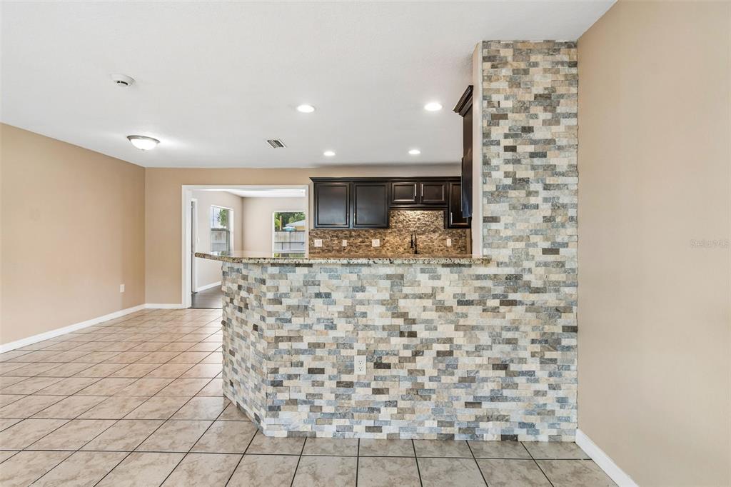 A kitchen features a stone-tiled breakfast bar, dark cabinetry, and light-colored floor tiles — 4018 PRADO DRIVE, SARASOTA, FL