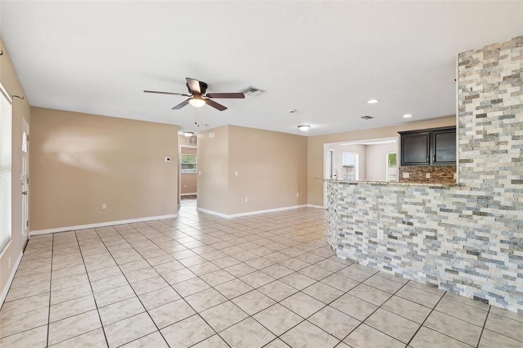 An open-concept living area features beige walls, tiled floors, and a stone-accented kitchen island — 4018 PRADO DRIVE, SARASOTA, FL