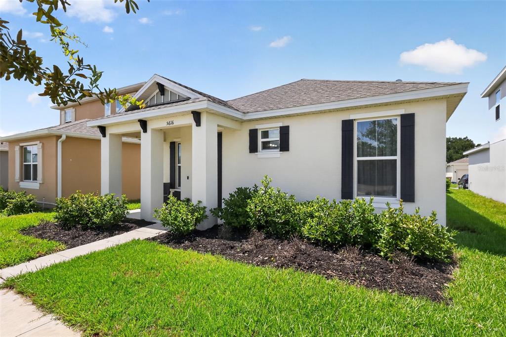 A single-story house with a beige stucco exterior, dark shutters, and a covered front porch — 5616 BEGGS ROAD, ST CLOUD, FL
