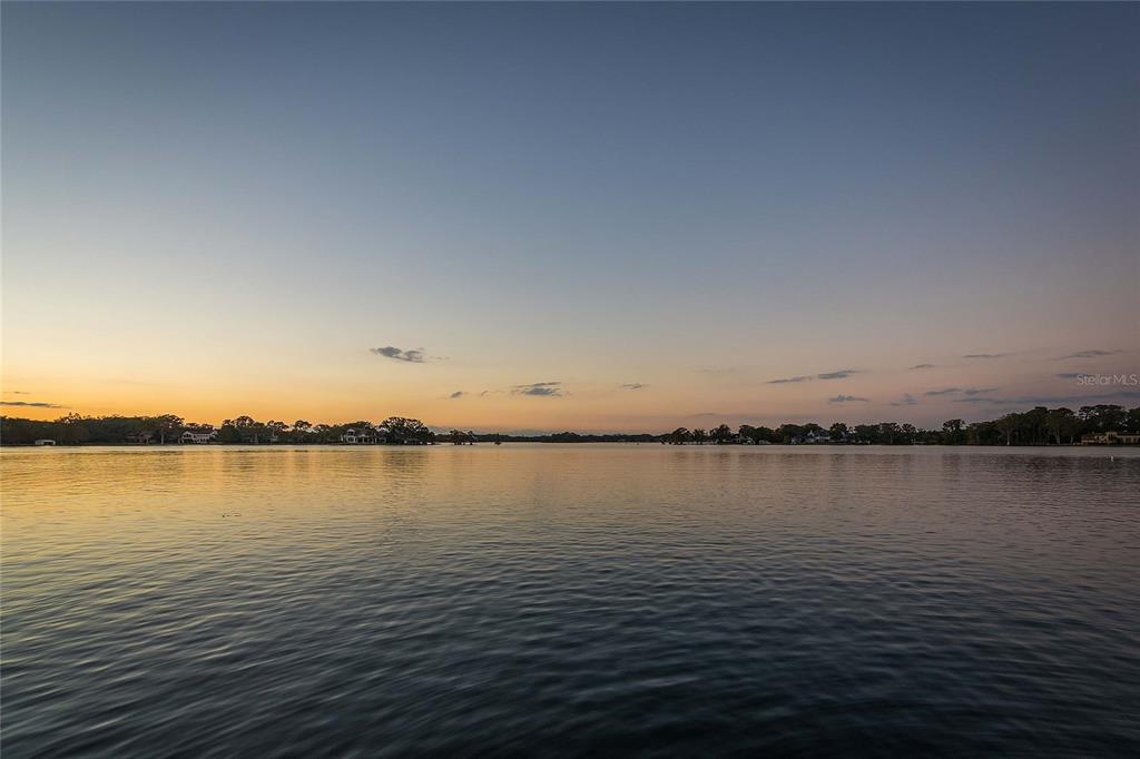 A wide view of a calm lake at sunset with distant treeline and houses — 1360 ALABAMA DRIVE, WINTER PARK, FL