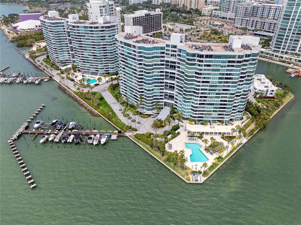 An aerial view shows high-rise residential buildings with a swimming pool and private boat docks — 888 BOULEVARD OF THE ARTS UNIT 1705, SARASOTA, FL