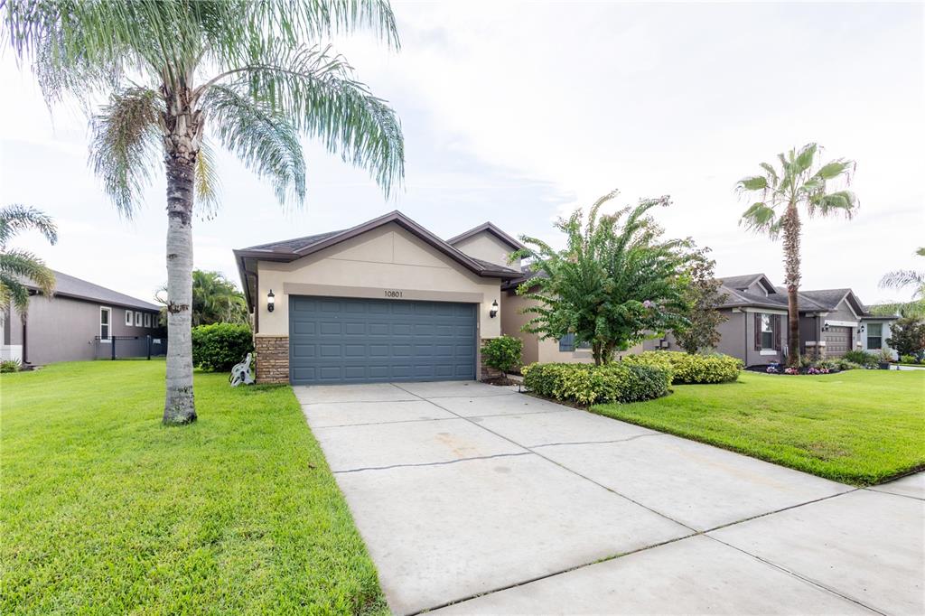 A single-story house with a two-car garage, a concrete driveway, and palm trees — 10801 52ND COURT E, PARRISH, FL