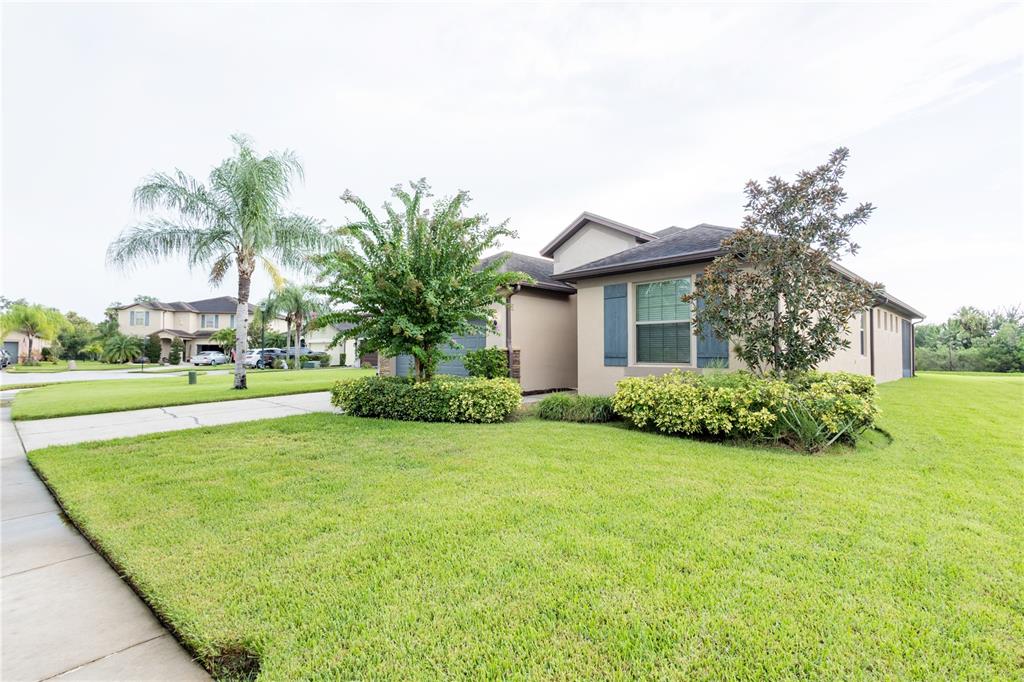 A single-story suburban house with a tan exterior, a green lawn, and mature landscaping — 10801 52ND COURT E, PARRISH, FL