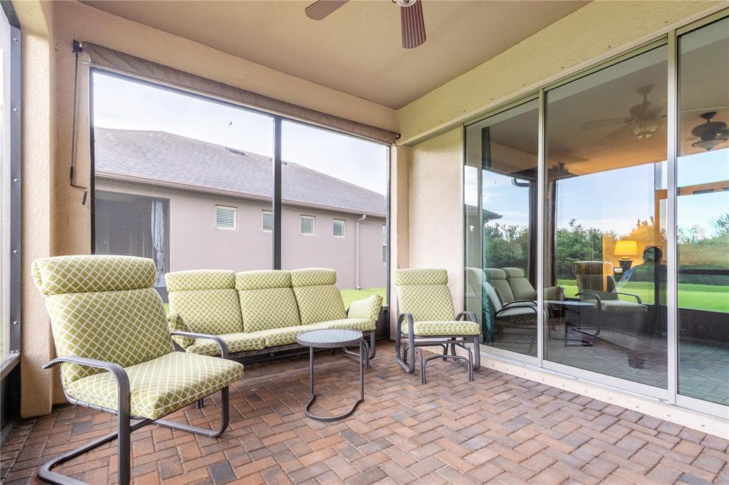A screened-in patio with brick flooring, outdoor furniture, and sliding glass doors leading indoors — 10801 52ND COURT E, PARRISH, FL