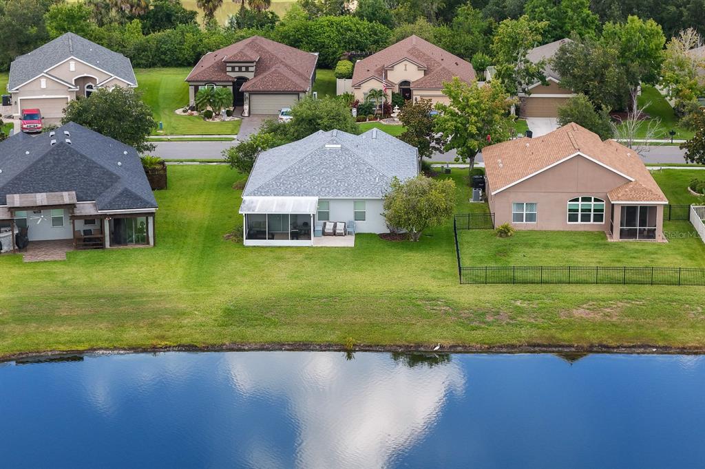 An aerial view shows three suburban houses with backyards facing a large pond — 11223 82ND STREET E, PARRISH, FL