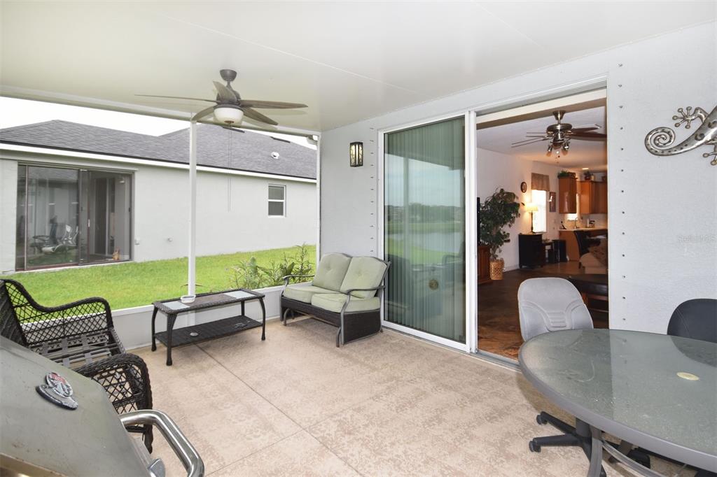 A covered patio features a ceiling fan, outdoor furniture, and sliding glass doors leading indoors — 11223 82ND STREET E, PARRISH, FL