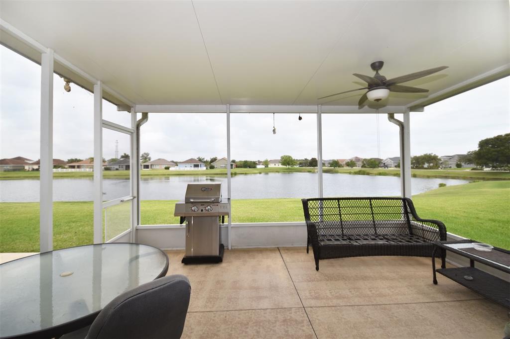 A screened-in patio features a grill, outdoor furniture, and a view of a lake — 11223 82ND STREET E, PARRISH, FL