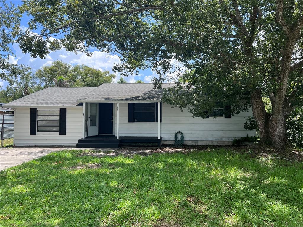 A single-story white house with black shutters and a front porch under a large tree — 225 MISSISSIPPI AVENUE, ST CLOUD, FL