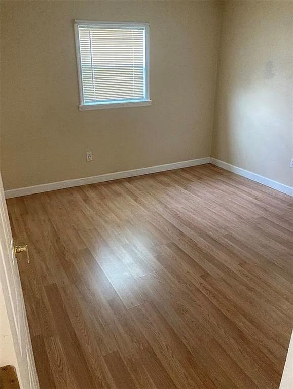 An empty room features light wood-look flooring, beige walls, and a single window with blinds — 225 MISSISSIPPI AVENUE, ST CLOUD, FL