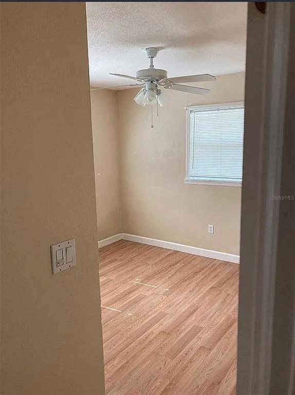 An empty bedroom features light-colored walls, wood-look flooring, and a ceiling fan with light fixtures — 225 MISSISSIPPI AVENUE, ST CLOUD, FL
