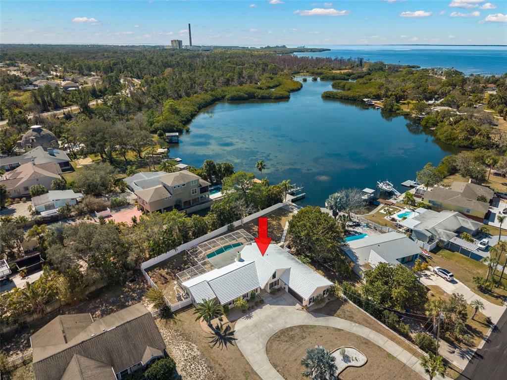 An aerial view shows a waterfront house with a pool and a circular driveway — 2138 BAYOU DRIVE, HOLIDAY, FL