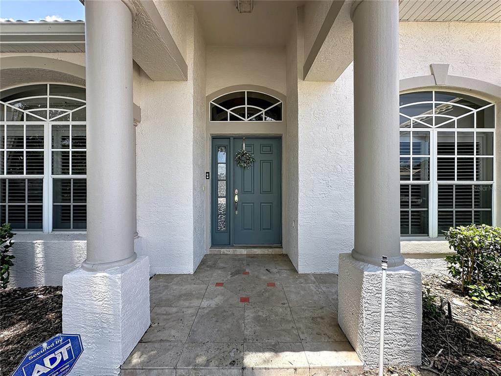 A front entryway features a blue door, two columns, and windows with white frames — 3916 SCARBOROUGH COURT, CLERMONT, FL