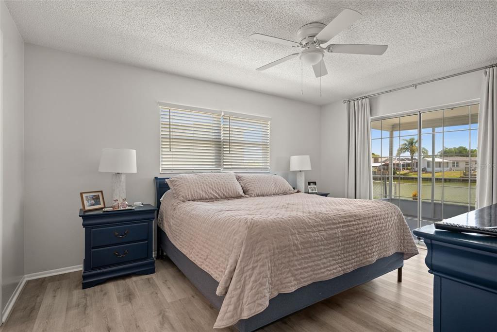 A bedroom features a bed with a quilted cover, blue nightstands, and a sliding glass door — 3132 JACKSON DRIVE, HOLIDAY, FL