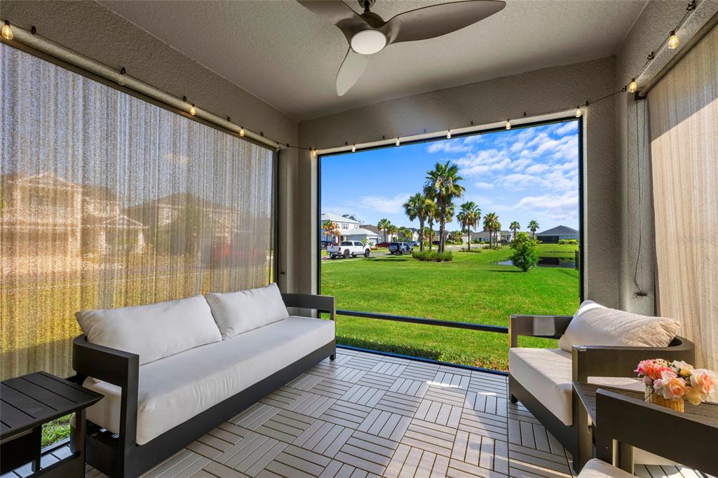 A screened-in patio with modern furniture, tiled flooring, and a view of a grassy neighborhood — 6365 SPRINGMONT LOOP, PALMETTO, FL