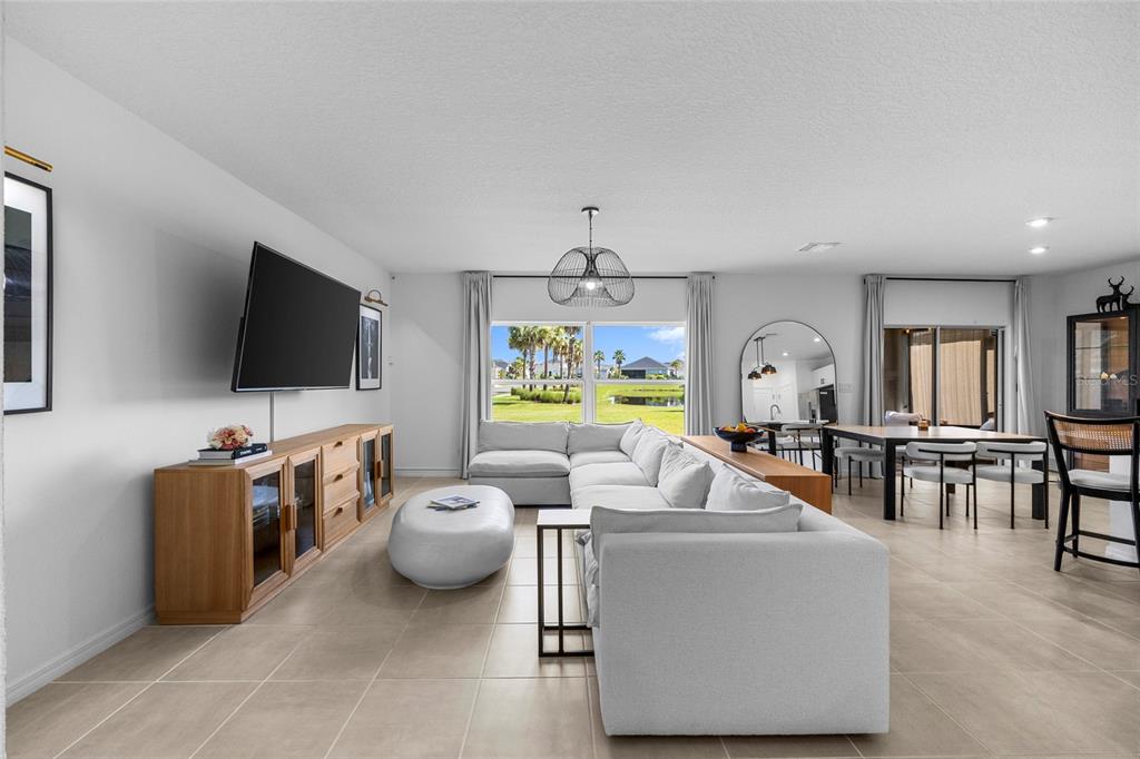 A bright, open-concept living room features a large sectional sofa, media console, and dining area — 6365 SPRINGMONT LOOP, PALMETTO, FL