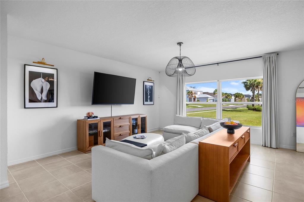 A living room features a light-colored sectional sofa, a wooden media console, and large windows — 6365 SPRINGMONT LOOP, PALMETTO, FL