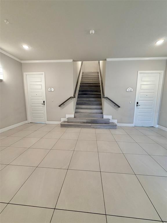 A modern living room features high ceilings, large windows, a gray sofa, and wall art — 7770 SANDY RIDGE DRIVE UNIT 207, REUNION, FL