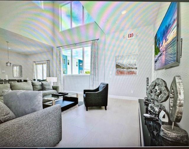 A golfer swings a club on a green course with a lake and buildings nearby — 7770 SANDY RIDGE DRIVE UNIT 207, REUNION, FL