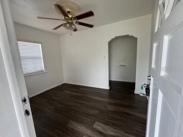 An empty room features dark wood-look flooring, a ceiling fan, and an arched doorway — 2506 W UNION STREET, TAMPA, FL