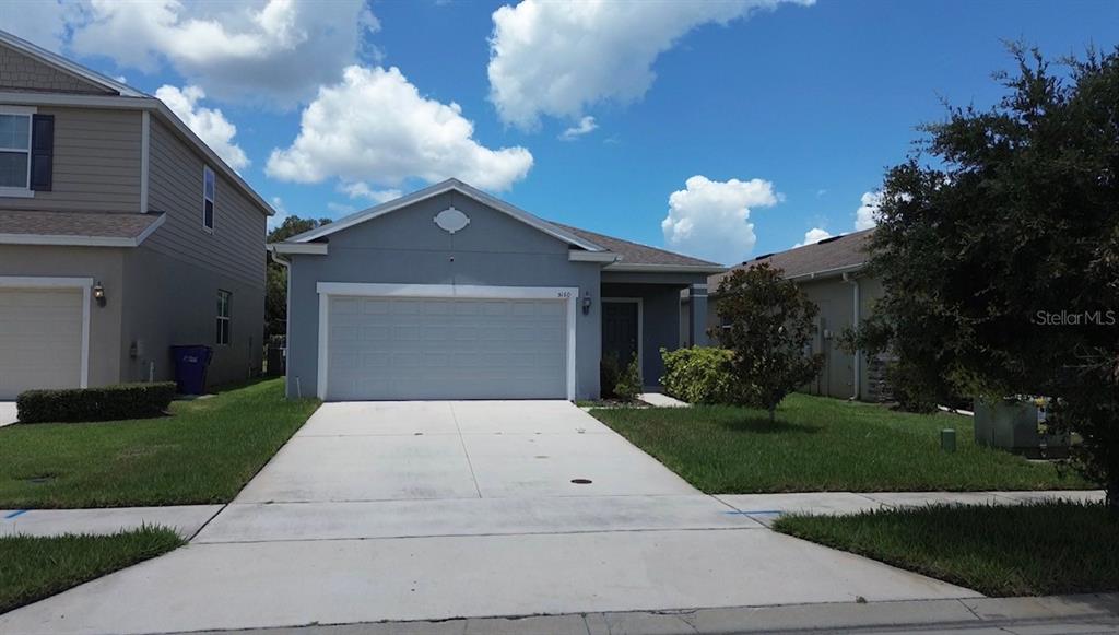 A single-story house with a light blue exterior, a two-car garage, and a concrete driveway — 5160 CHICKADEE STREET, ST CLOUD, FL