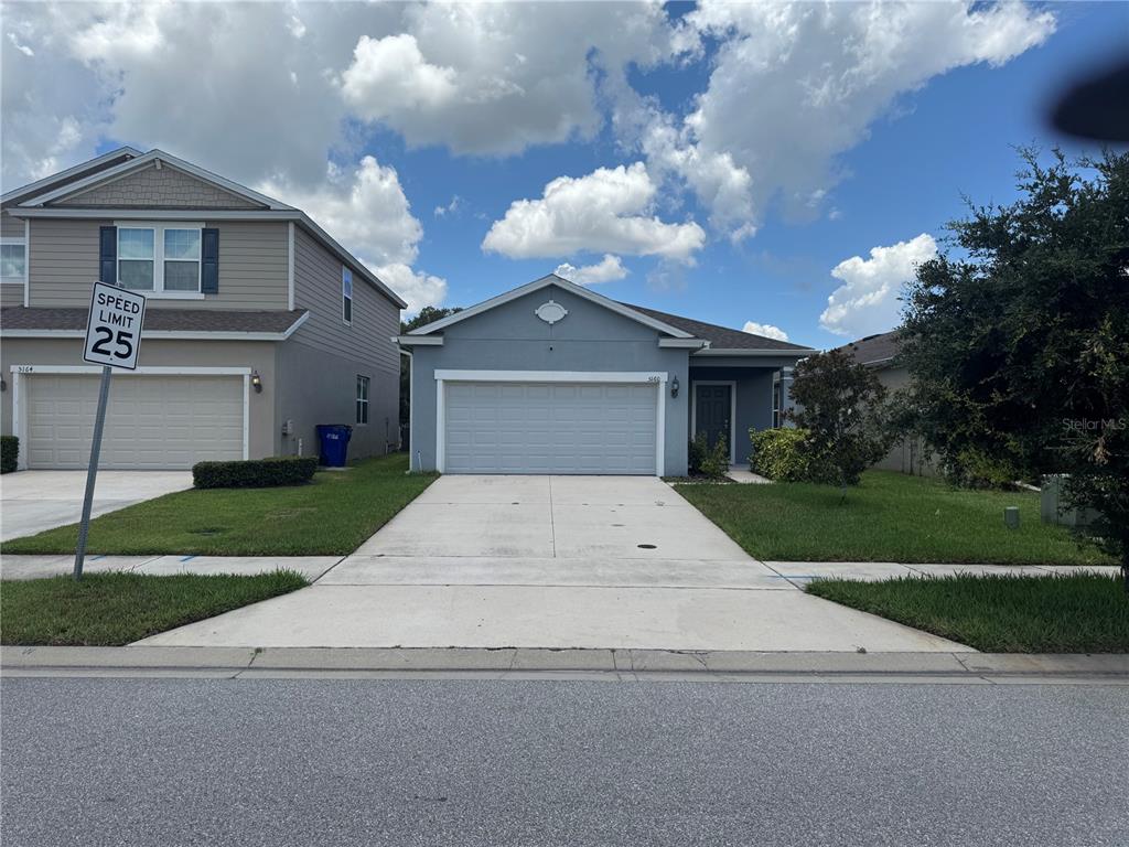 A single-story house with a gray exterior, a two-car garage, and a concrete driveway — 5160 CHICKADEE STREET, ST CLOUD, FL