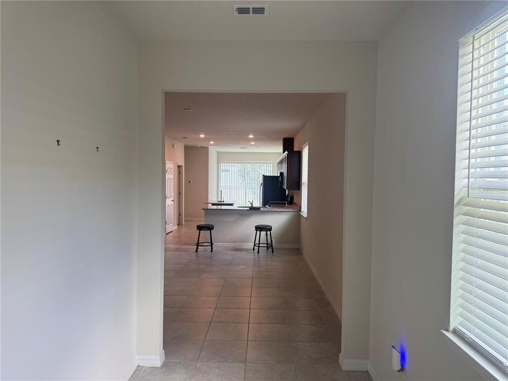 A view through a doorway into a kitchen with tile flooring and a breakfast bar — 5160 CHICKADEE STREET, ST CLOUD, FL