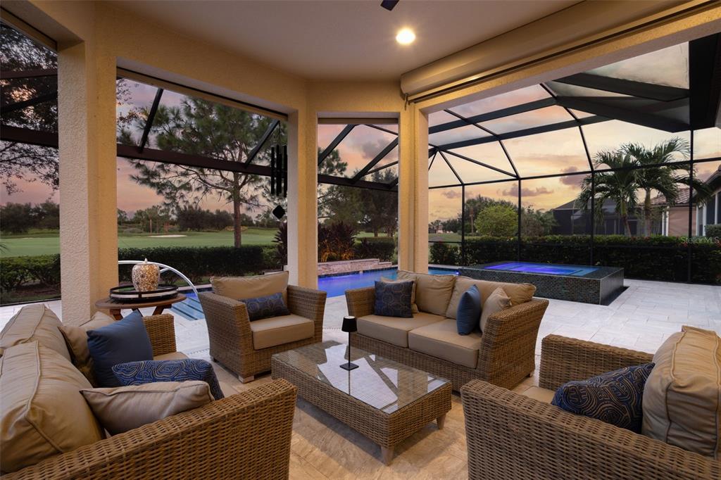 A covered patio features wicker furniture, a glass coffee table, and a view of a pool — 12807 SORRENTO WAY, BRADENTON, FL