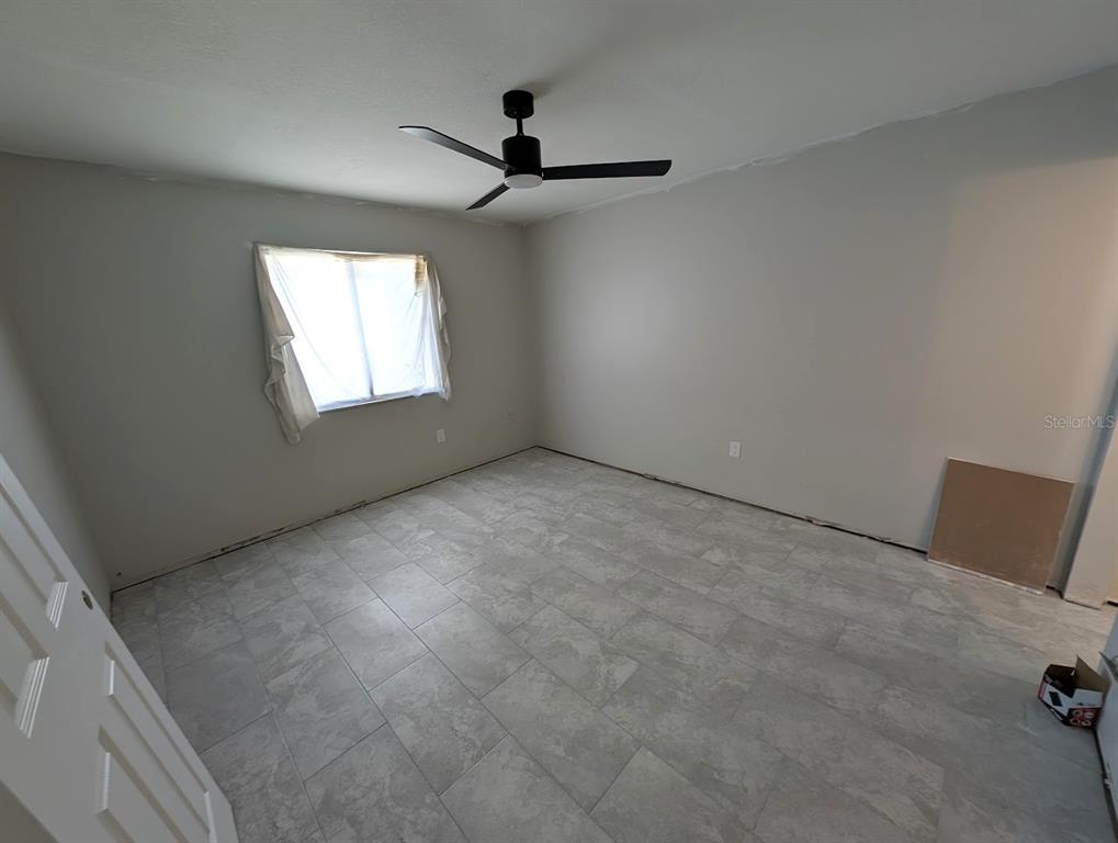 A closet features a white shelving unit, two metal hanging rods, and gray tile flooring — 2888 BANCROFT CIRCLE E UNIT 5B, PALM HARBOR, FL