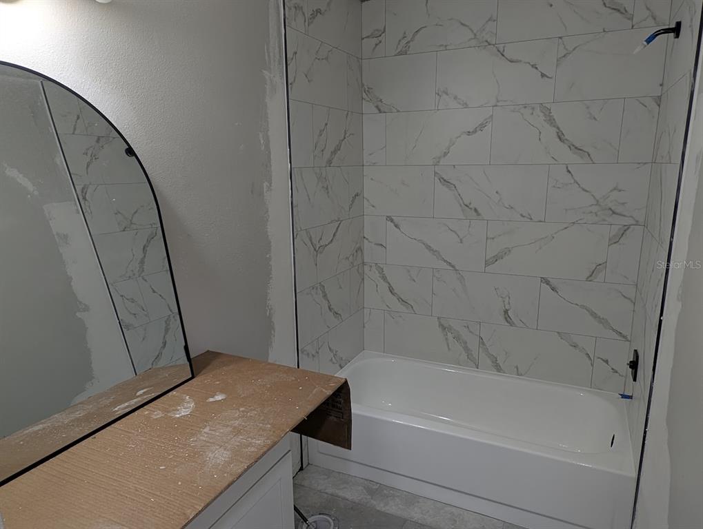 A shower with white marble-look wall tiles, a black niche, and black hexagonal floor tiles — 2888 BANCROFT CIRCLE E UNIT 5B, PALM HARBOR, FL