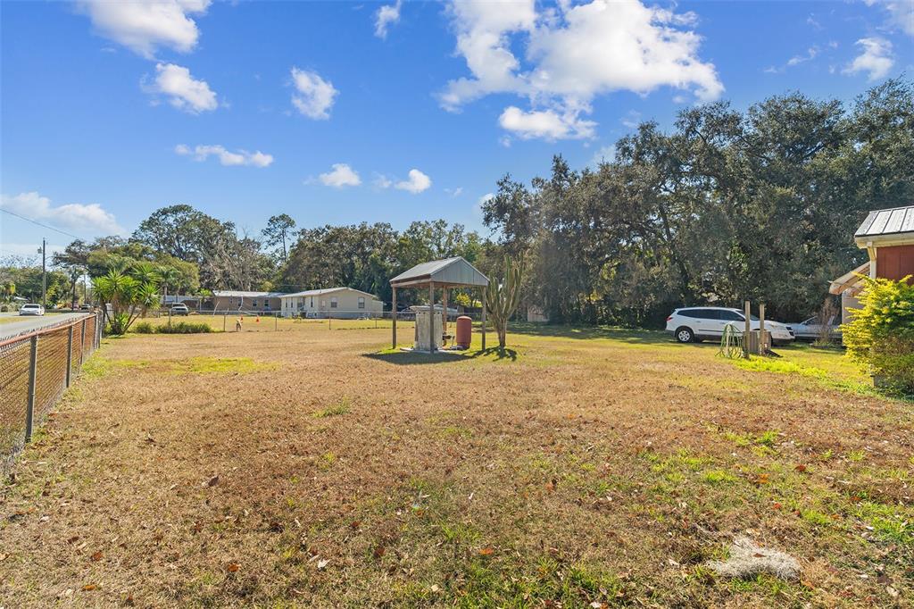 A grassy, fenced-in yard features a small covered well structure and mature trees — 5040 S KALIGA DRIVE, ST CLOUD, FL