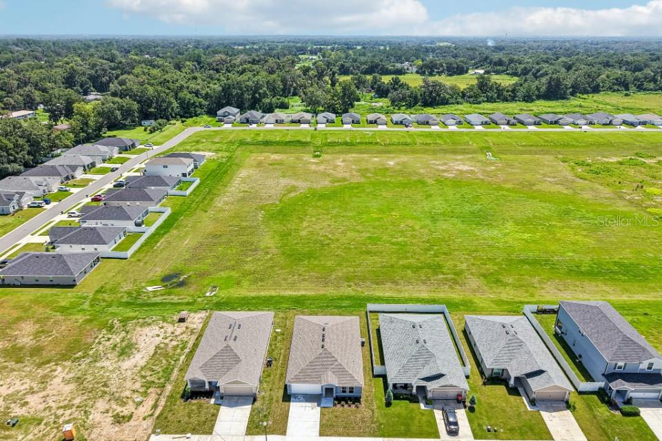 An aerial view shows a large grassy field surrounded by suburban houses and trees — 12841 SE 53RD COURT, BELLEVIEW, FL