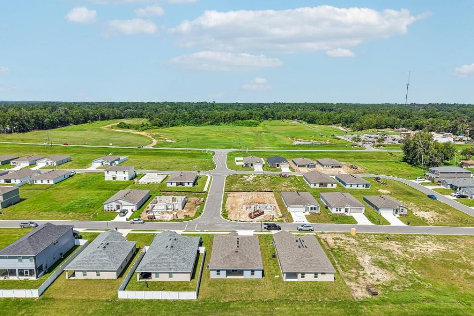 An aerial view shows a suburban neighborhood with several completed houses and active construction sites — 12841 SE 53RD COURT, BELLEVIEW, FL