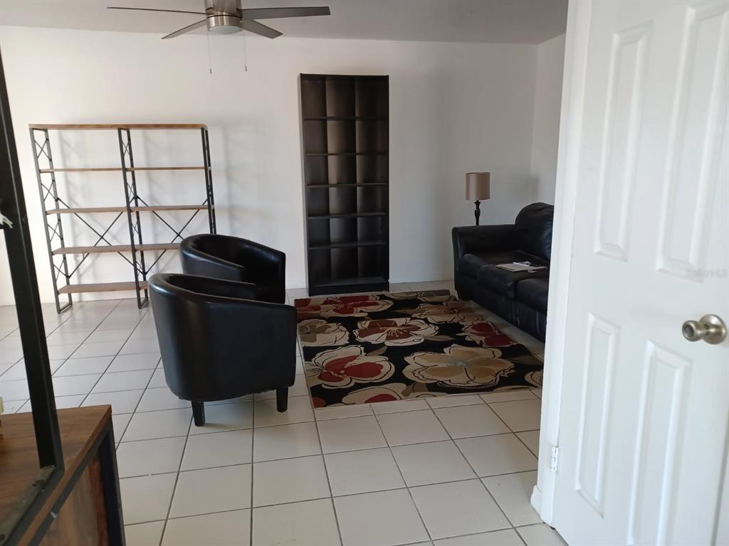 A living room features tiled floors, two black armchairs, a sofa, and two shelving units — 530 CASCADE CIRCLE UNIT 100, CASSELBERRY, FL