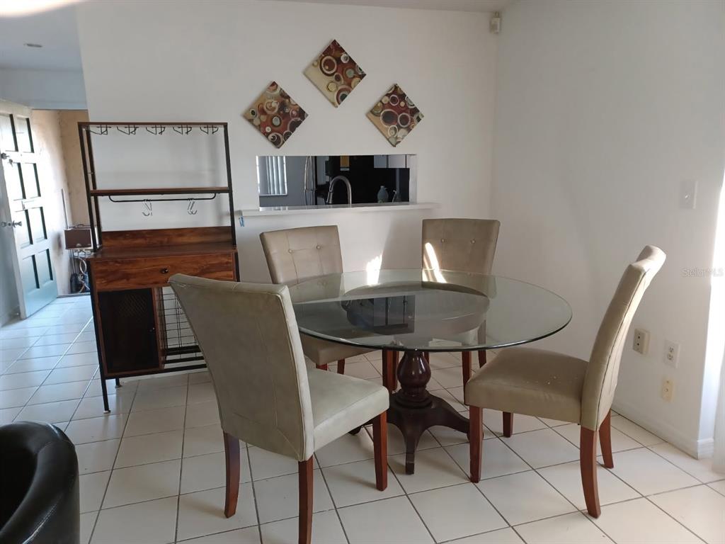 A dining area features a glass-topped table, four upholstered chairs, and a wooden wine rack — 530 CASCADE CIRCLE UNIT 100, CASSELBERRY, FL