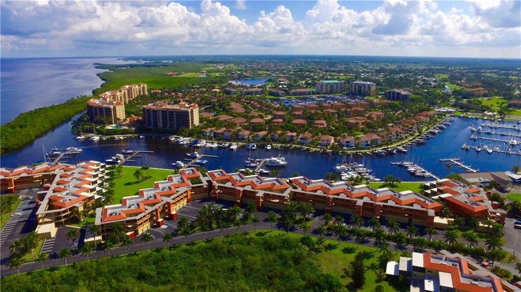 An aerial view of a waterfront residential complex with boat slips and surrounding green space — 24417 BALTIC AVENUE UNIT 1102, PUNTA GORDA, FL